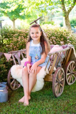 Ein Vorschulkind sitzt auf einem Bollerwagen. Kindergartenfotograf Weissenhorn