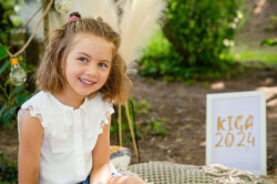 Guter Kindergartenfotograf gesucht? Kiga-Legends. Ein Mädchen sitzt auf einem Teppich im Garten der Kita