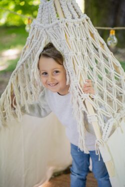 Ein Junge schaut lustig aus einem Boho-Zelt beim Kitashooting in Blaustein