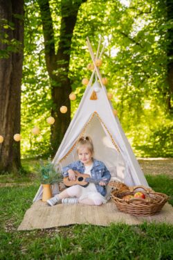 Ein Mädchen sitzt in einem Zelt und spielt Gitarre bei einem Kigafoto-Tag in Illertissen